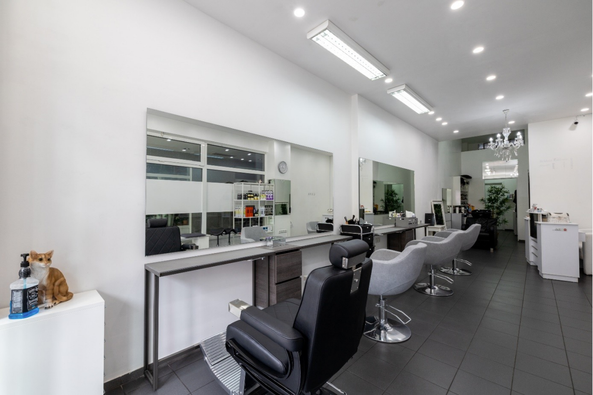 Seitlicher Blick auf die Friseursitze mit zwei Spiegeln – moderne Doppelarbeitsplätze mit großzügigen, freistehenden Spiegeln, die optimale Sicht von beiden Seiten ermöglichen und durch stilvolles Design den Salonraum elegant strukturieren